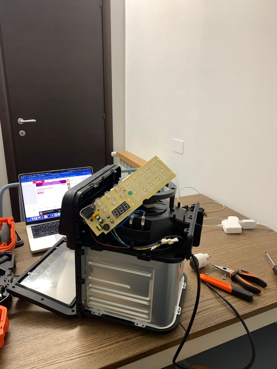 The oven with its top cover lifted, showing the control board and the wiring underneath.