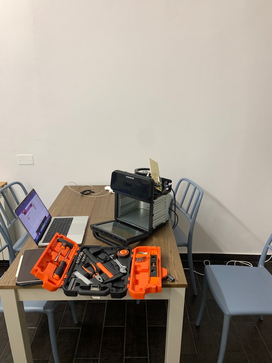 The open oven on the table next to a laptop and an orange toolbox.